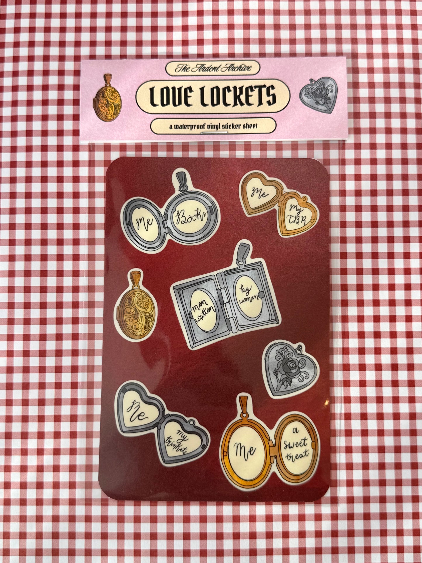 Red sticker sheet with lockets in plastic packaging with pink header card on red gingham background