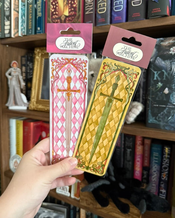 Two Sword Bookmarks in plastic in front of a bookshelf