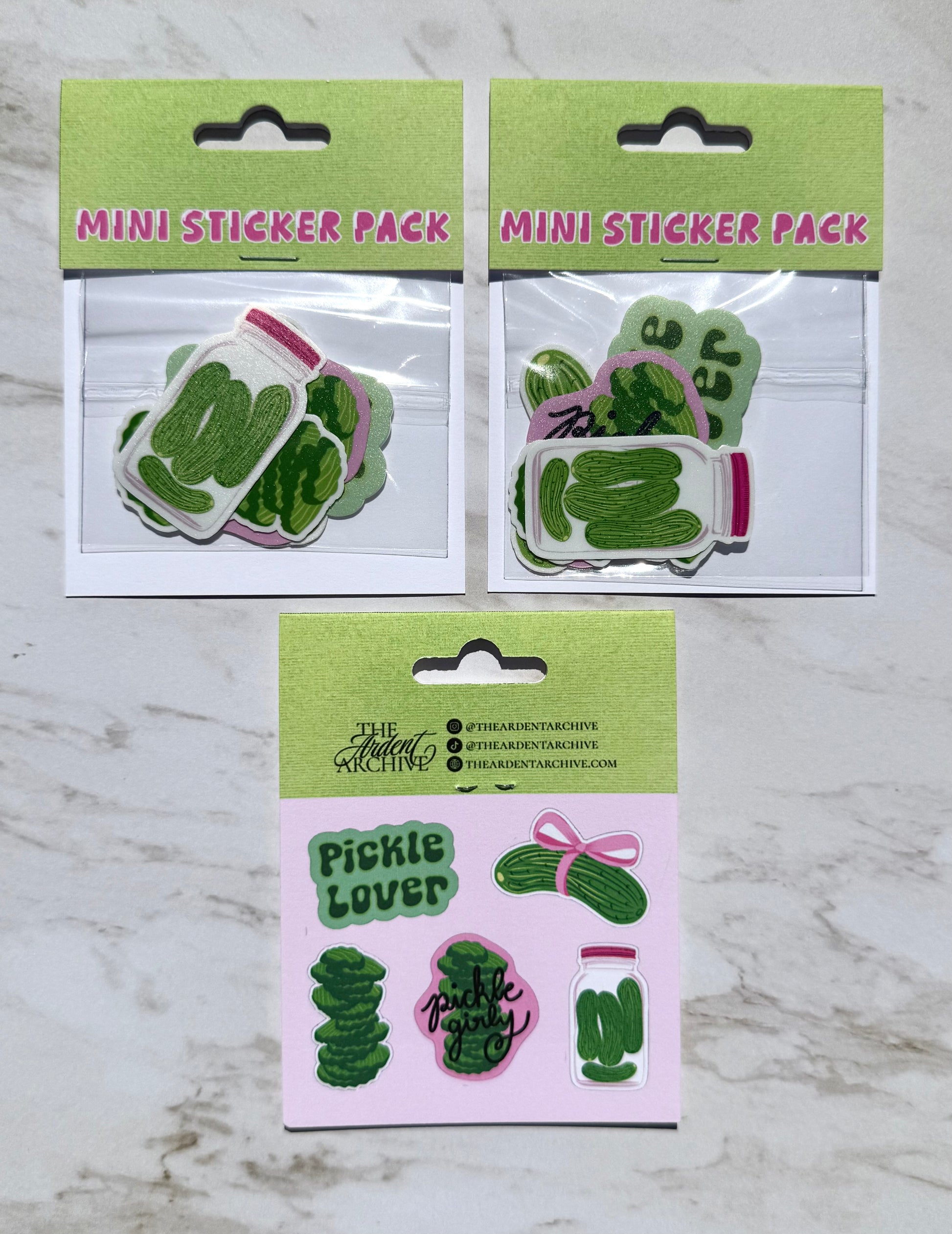 Two mini sticker packs with pickle-themed designs on a marble surface.