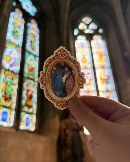 Hand holding a decorative item with stained glass windows in the background