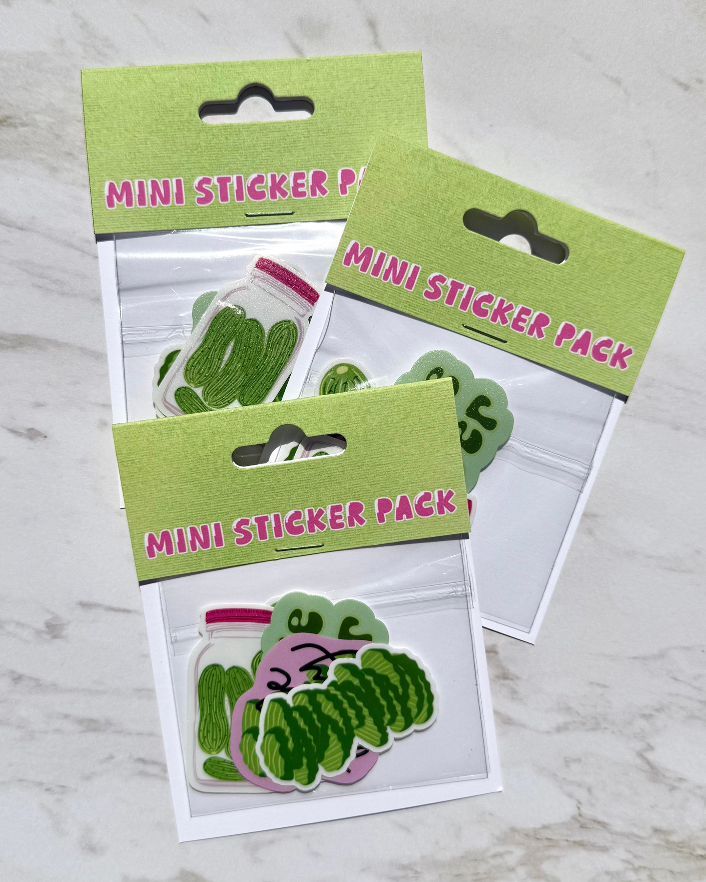 Three mini sticker packs with green and pink designs on a marble surface