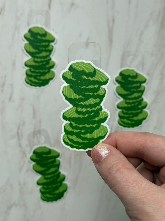 Green stacked circle stickers held by a hand against a light gray background