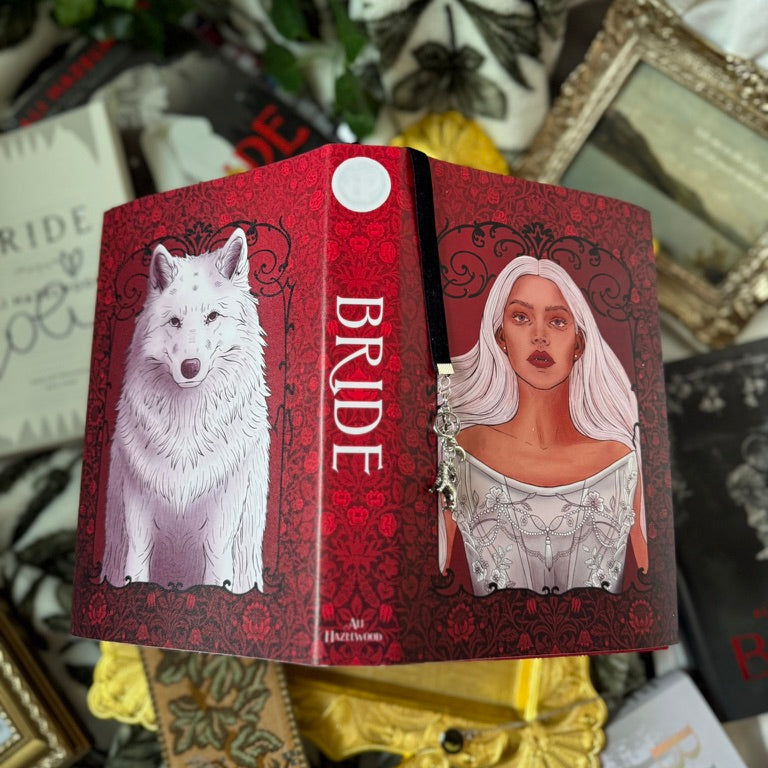 Red book with illustrations of a wolf and a woman, surrounded by decorative items.