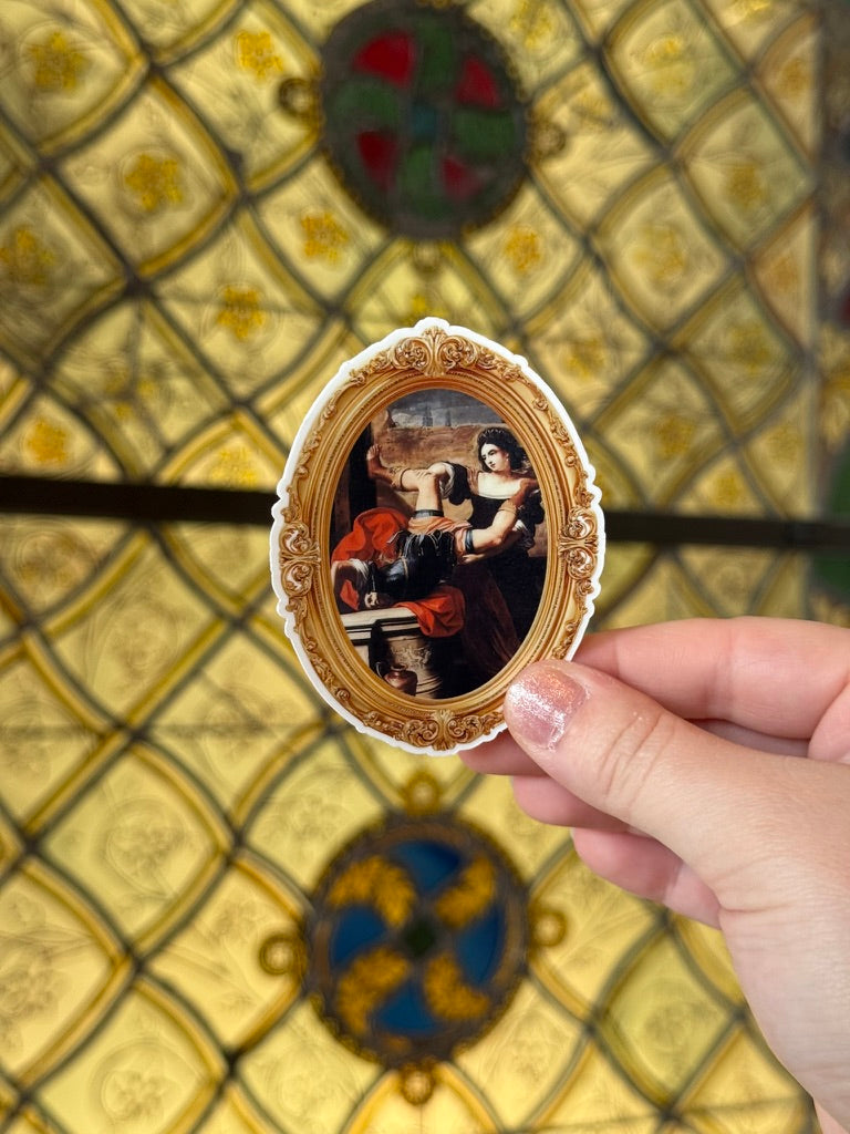 Small framed artwork held by a hand against a decorative tiled wall.