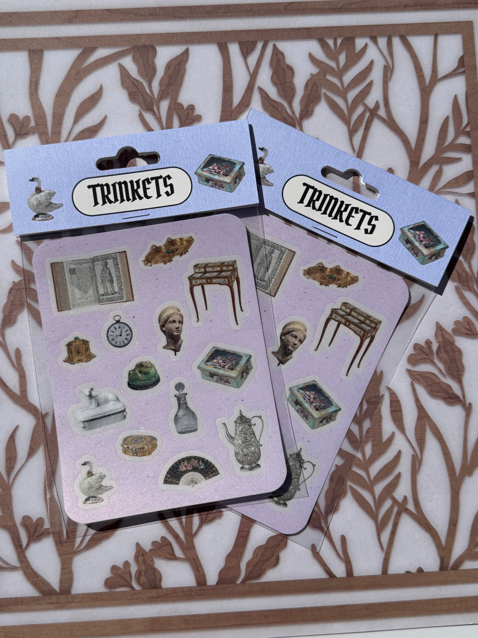 Two packages of 'Trinkets' stickers on a decorative background