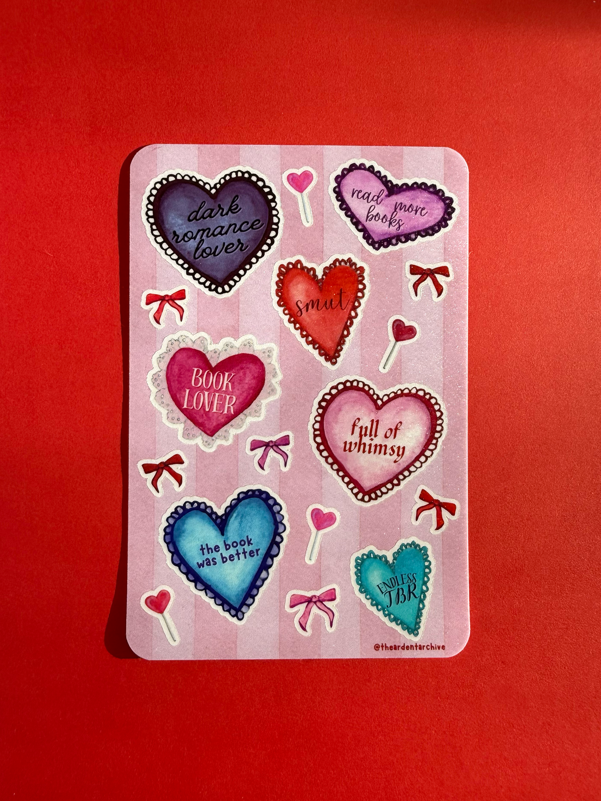 Sticker sheet with watercolored heart-shaped designs on a red background.
