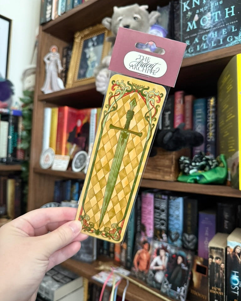 Sword Bookmark in plastic in front of a bookshelf