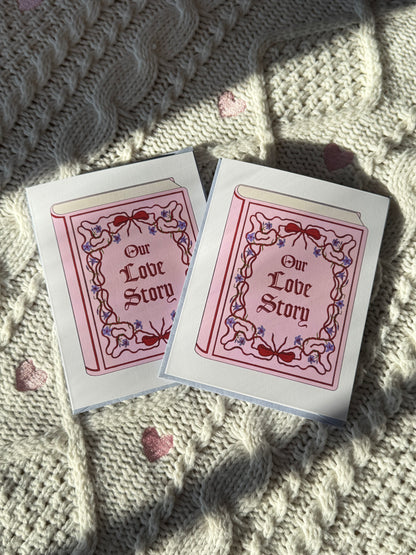 Two 'Our Love Story' greeting cards on a textured fabric surface