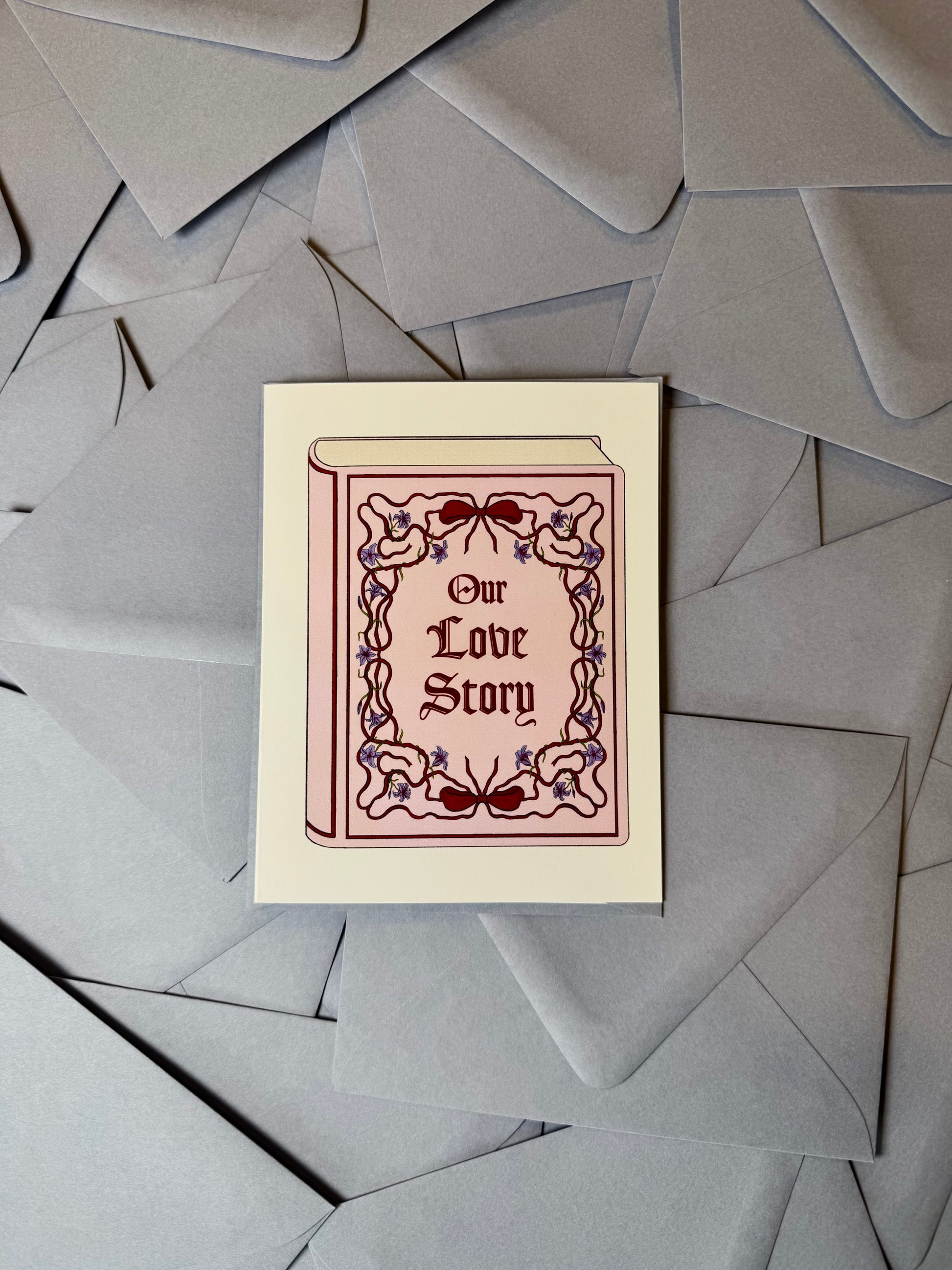 Greeting card with 'Our Love Story' design on a background of gray envelopes