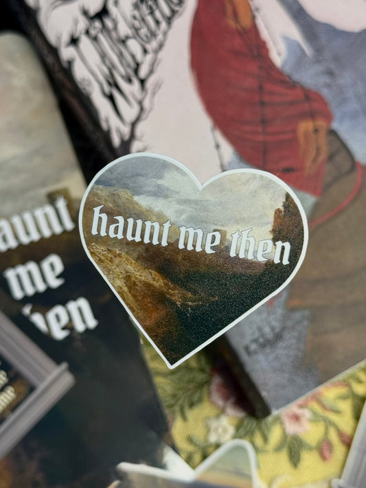 Heart-shaped sticker with 'haunt me then' text on a book background