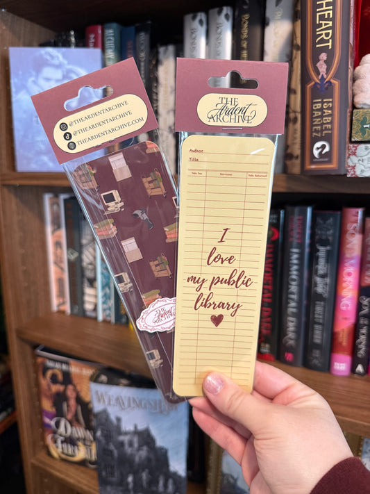 Two bookmarks with text held in front of a bookshelf filled with books.