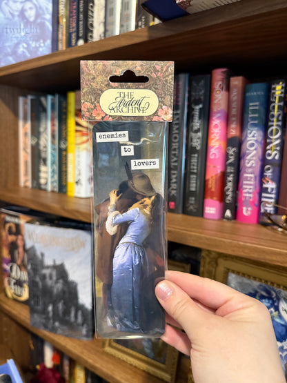 Packaged bookmark with 'The Ardent Archive' branding held in front of a bookshelf.