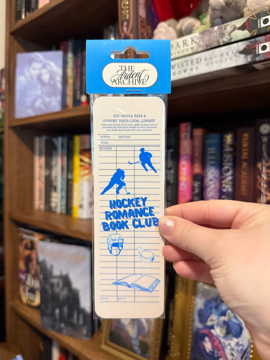Hockey Romance Book Club bookmark held in front of a bookshelf with books.