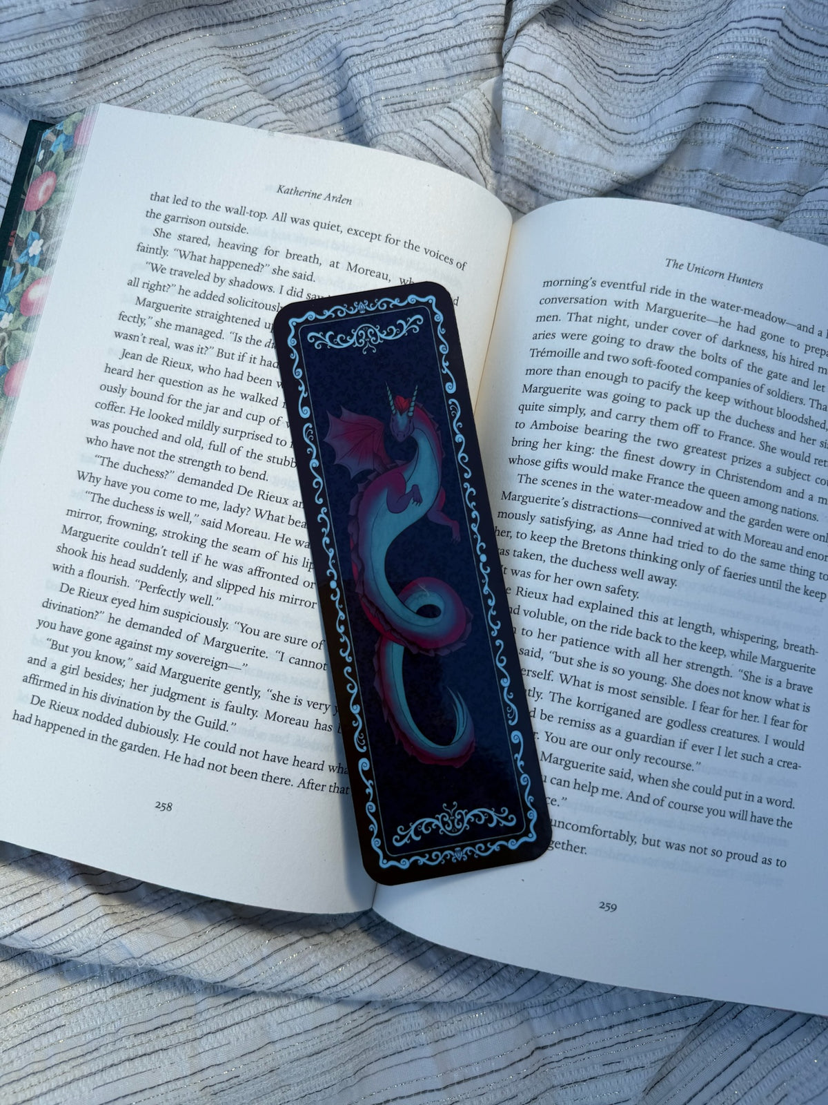 A rectangular black bookplate with a blue and purple swirling design and ornate blue borders, placed on an open book.
