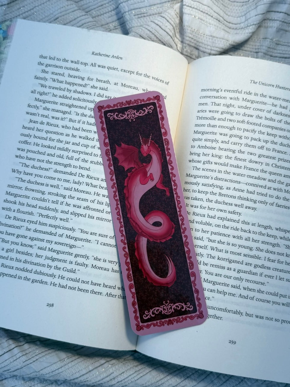 A red and black decorative book bookmark with a heart-shaped cutout, placed on an open book page.