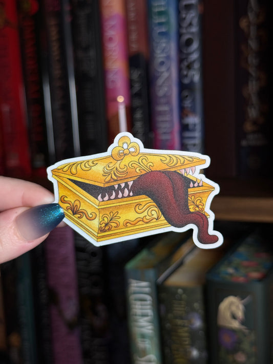 hand holding a gold jewelry box with tongue and teeth